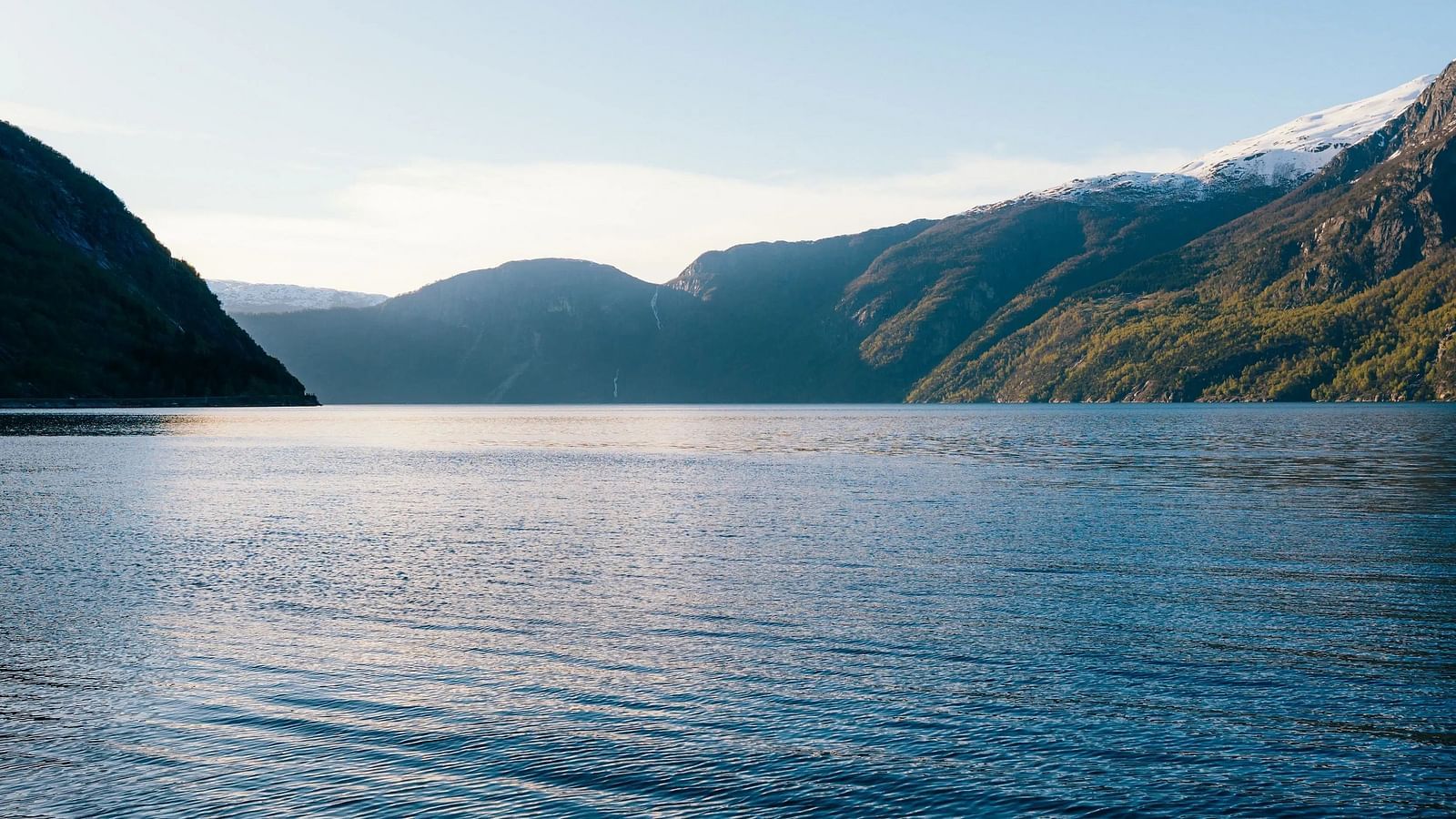 Water stretches into the distance, framed by hills under a clear sky.