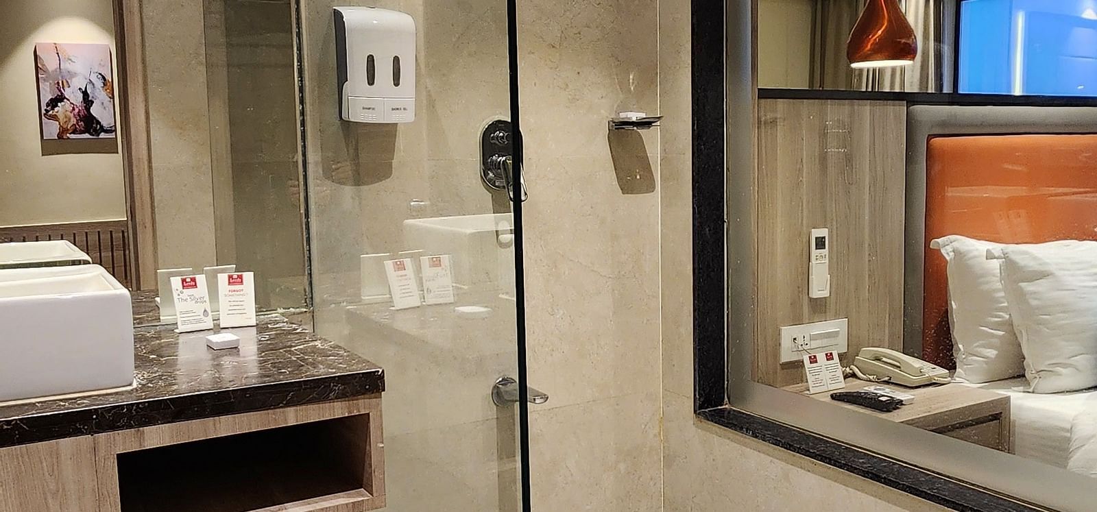 Glass-panelled bathroom in a hotel suite, featuring a walk-in shower and modern fixtures.