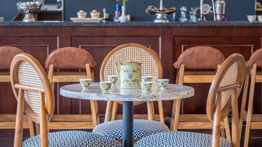  A brightly lit interior of a restaurant featuring a round marble-topped table with a black pedestal base is centered in the foreground - Vishranti Resort, Dehradun