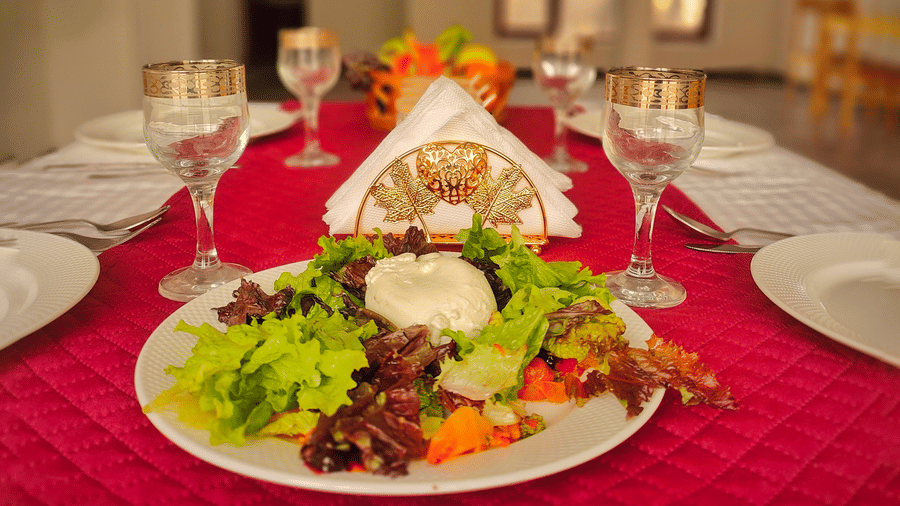 A beautifully arranged dining table featuring a salad dish as a centrepiece in the dining hall at Indus Serenity Retreat.