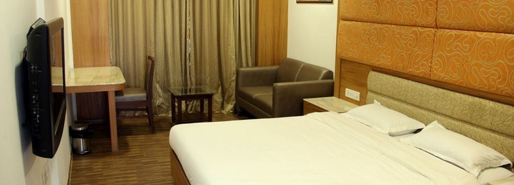 Well-lit hotel room with large bed, work desk, and TV