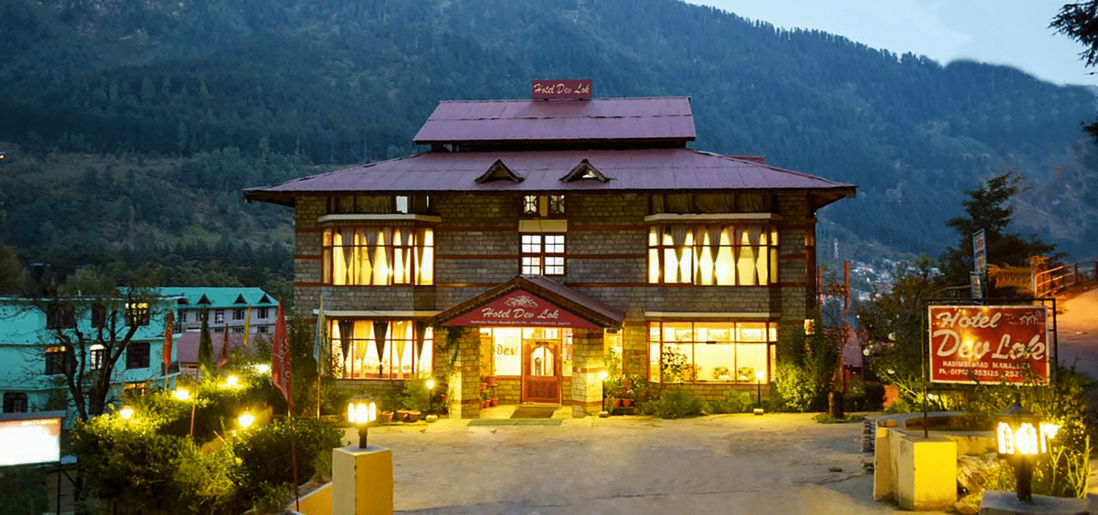 Exterior of DLS Hotel Devlok, Manali during dusk with the mountains in the backdrop