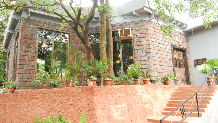 Exterior view of a rustic brick-and-stone resort building with potted plants and concrete steps.