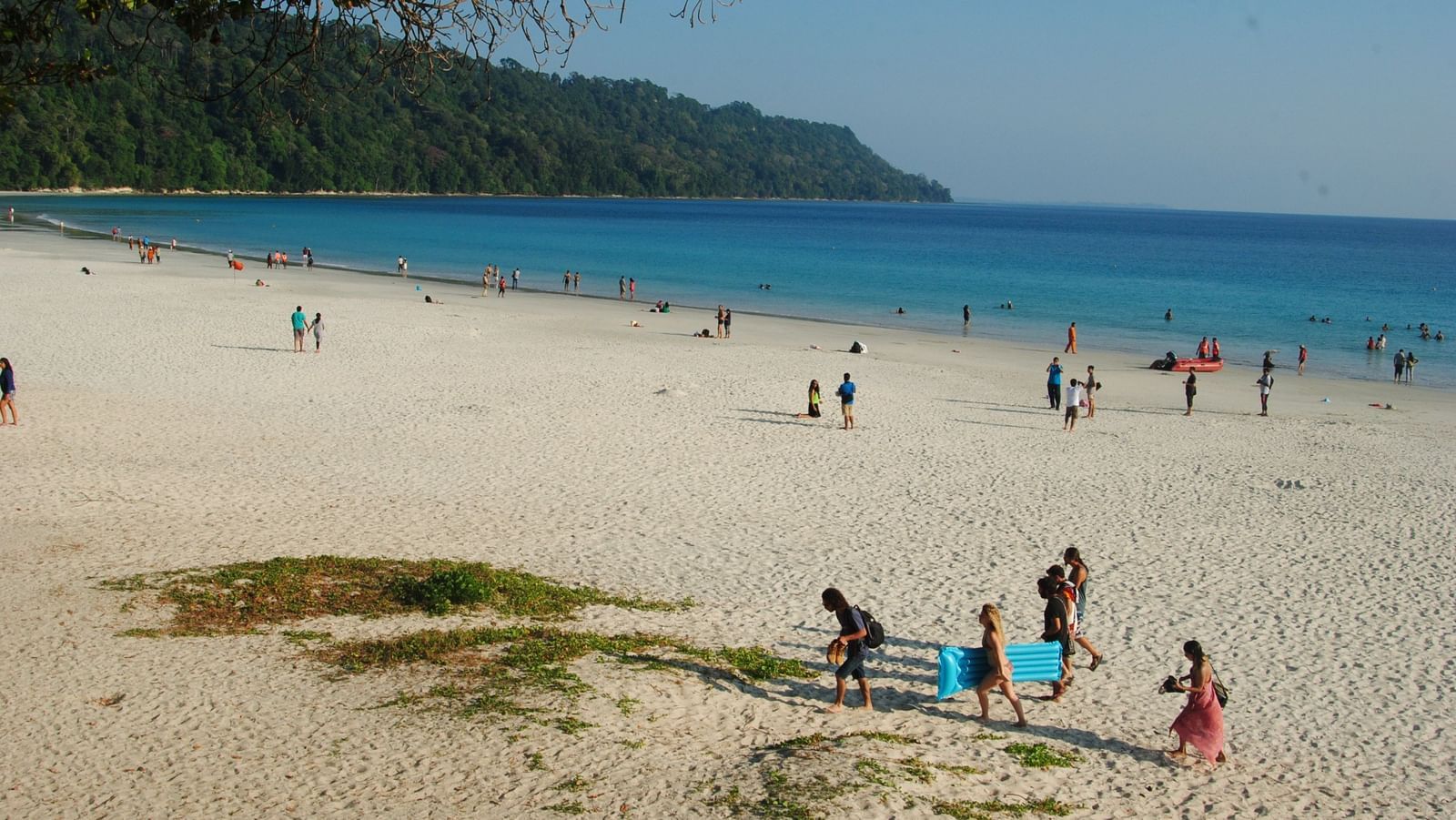 Tourists playing on the beach with a vast blue ocean in the background at Radhanagar beach.