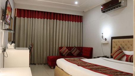 Guest room with bed, window drapes and seating area at Hotel Diamond Plaza, Chandigarh