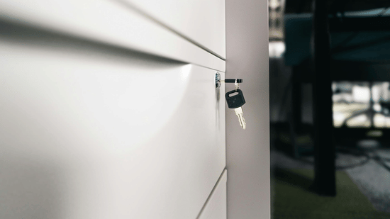A close-up of a cabinet door with a key inserted into the lock.
