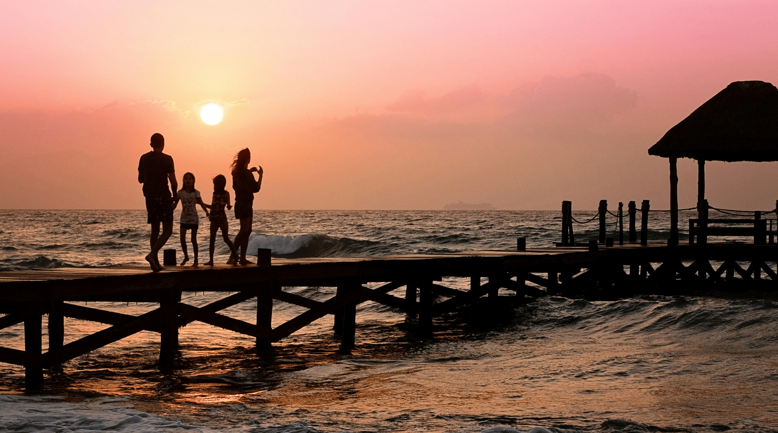 A family walking on a pier during sunset
