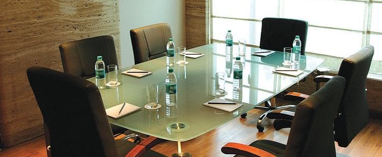 Image of a meeting room at our hotel featuring a glass table with seven chairs around it. | Mirage Hotel