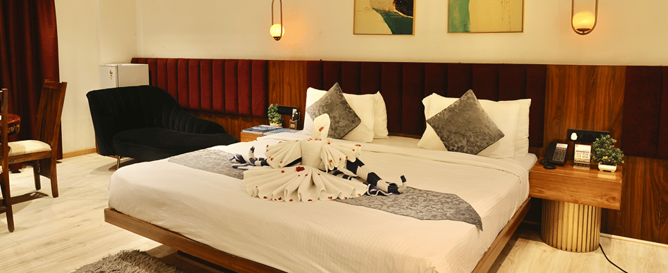 Club Suite with a king bed dressed with swan towel art beneath pendant lights and framed artwork