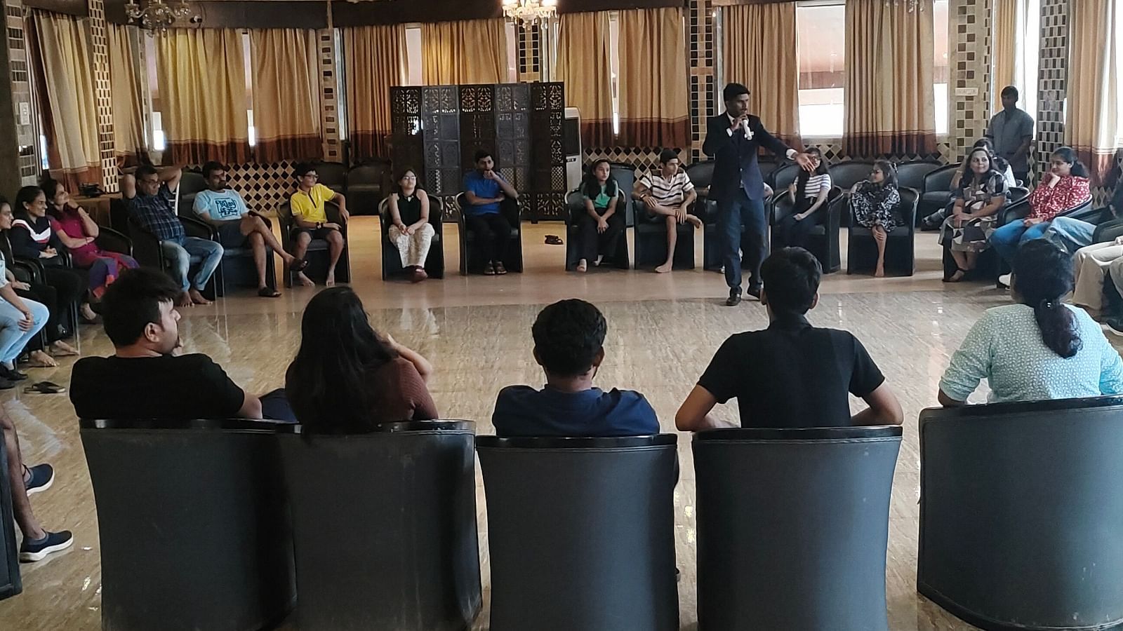Image of a group of guests sitting in a circular pattern playing a group game | The Grand Legacy Resort and Spa