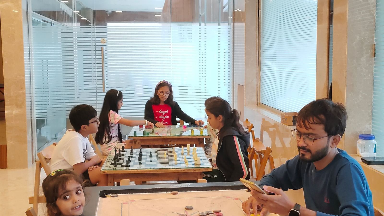 Image of a group of people playing carrom at the activity zone of the resort | The Grand Legacy Resort and Spa