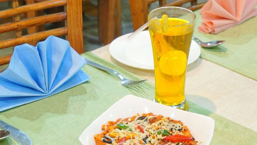 A dining table with a neatly decorated cloth, featuring a plate of pasta and a refreshment beside it at DLS Hotels The Rock Castle.