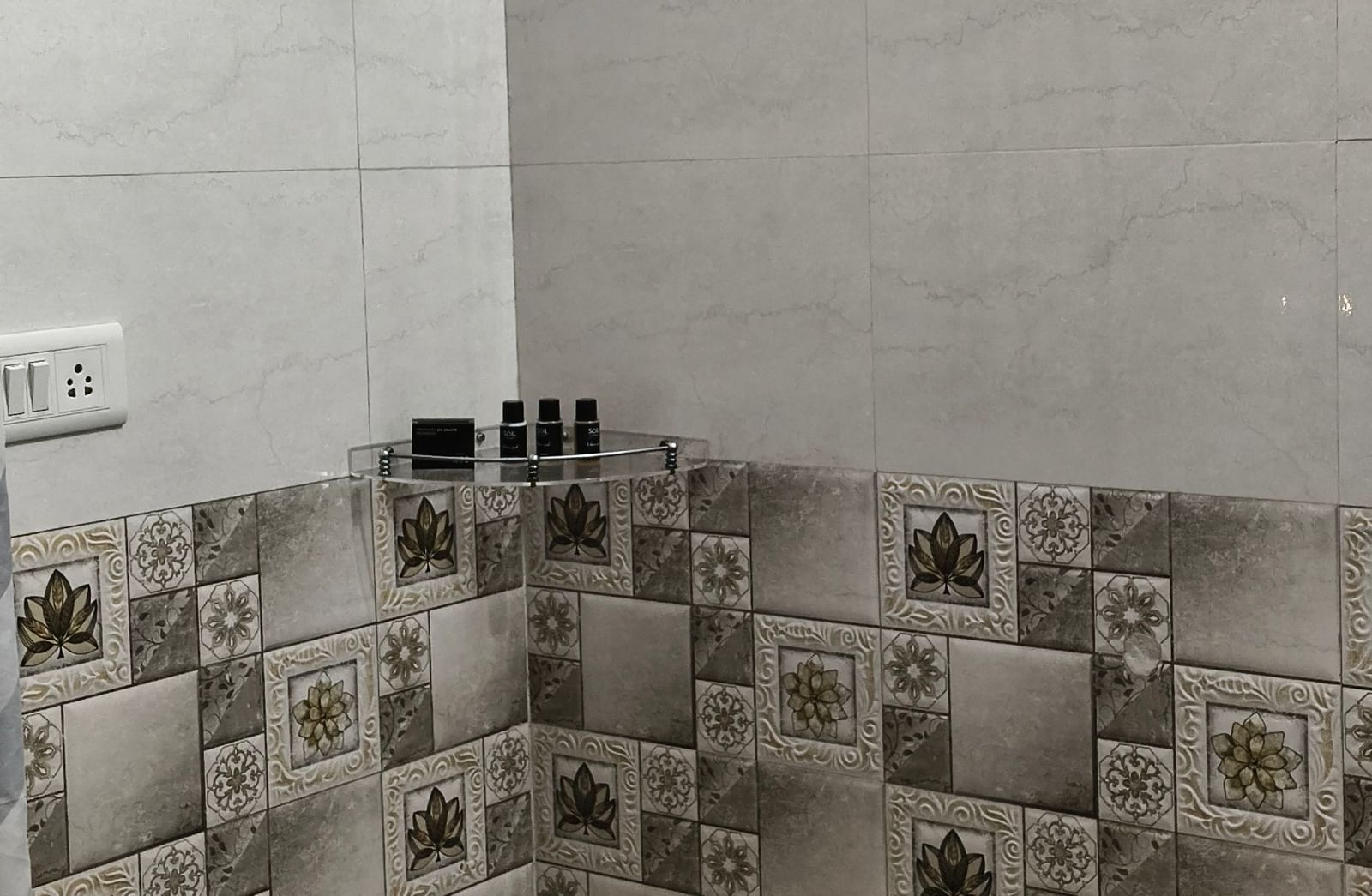 A bathroom featuring grey tiles, a shower, bucket and modern fittings seen from the doorway at Jaypore360 Homestay - Best Rooms in Jaipur.