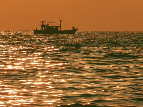 sunset view with a boat travelling in the ocean in chennai 