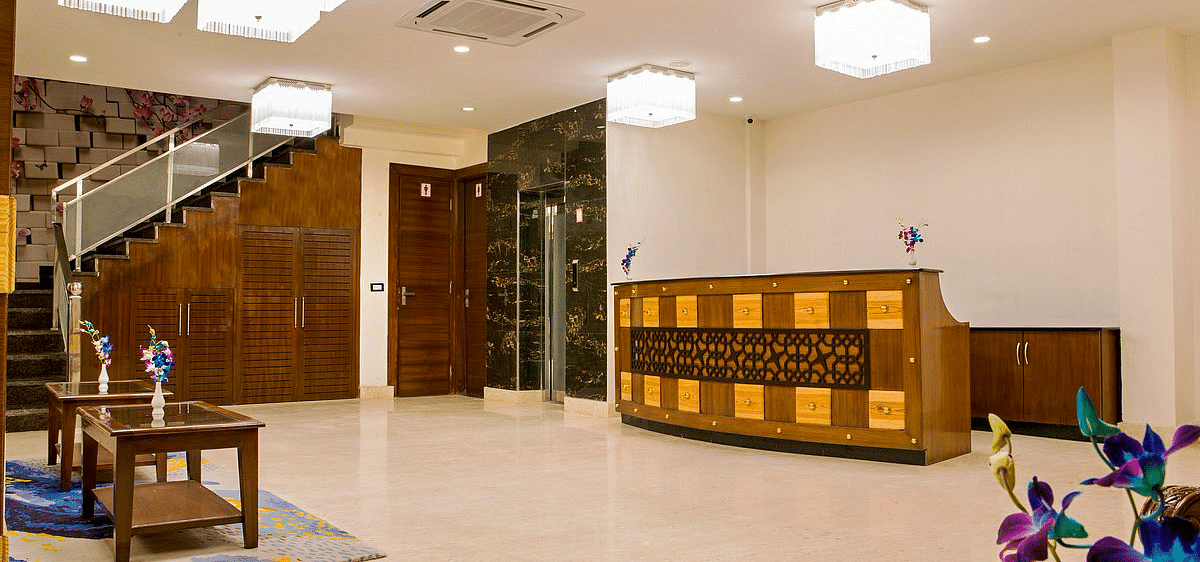 A brightly lit reception area featuring a reception desk in the far end at Regenta Inn DLA.