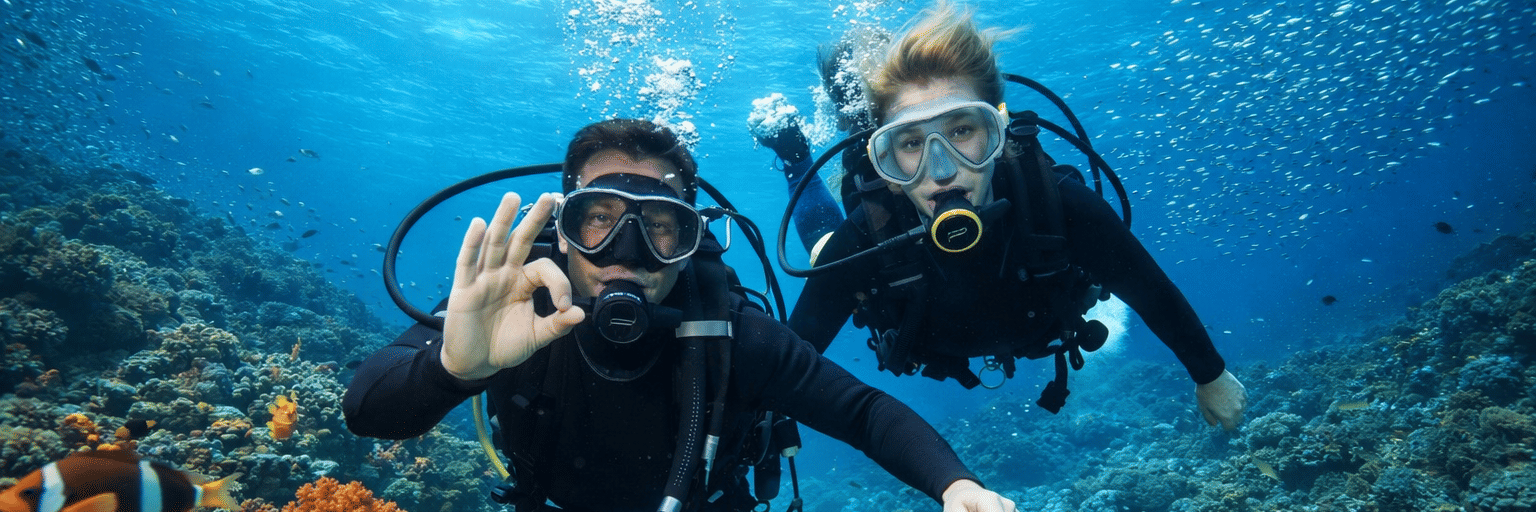 A couple of scuba divers underwater near reefs with fish swimming around