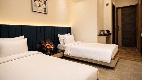 Deluxe Twin Room at Lords Swastik Studio, Kodinar featuring two single beds, contemporary interiors, air conditioning, elegant lighting, and modern in-room amenities for a comfortable stay.