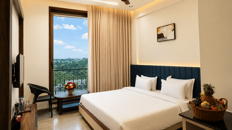 Deluxe King Room at Lords Swastik Studio, Kodinar with a king-size bed, modern interiors, large window overlooking scenic views, work desk, and premium amenities for a relaxing stay.