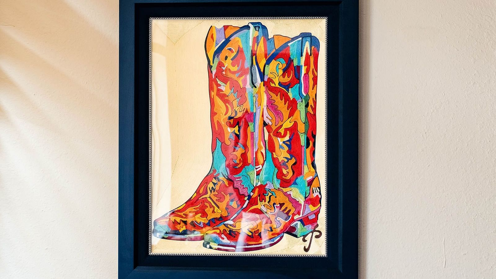 A framed abstract painting hanging on a light-colored wall, giving a artistic touch.- The Grand Hotel & Ballroom, McKinney