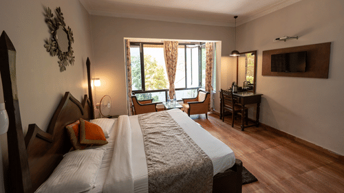 Side view of the cosy bed and a wide window at Himalaya Hotel, Nainital