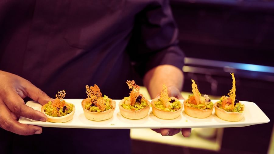 a close up shot of a chef holding a plate of dessert - Rhythm Gurugram