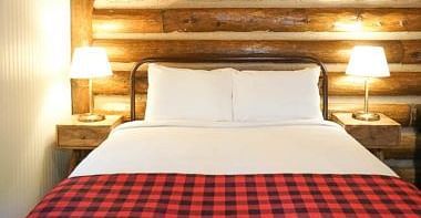 A room with a double bed and side tables with night lamps placed on it -Shaver Lake Village Hotel.