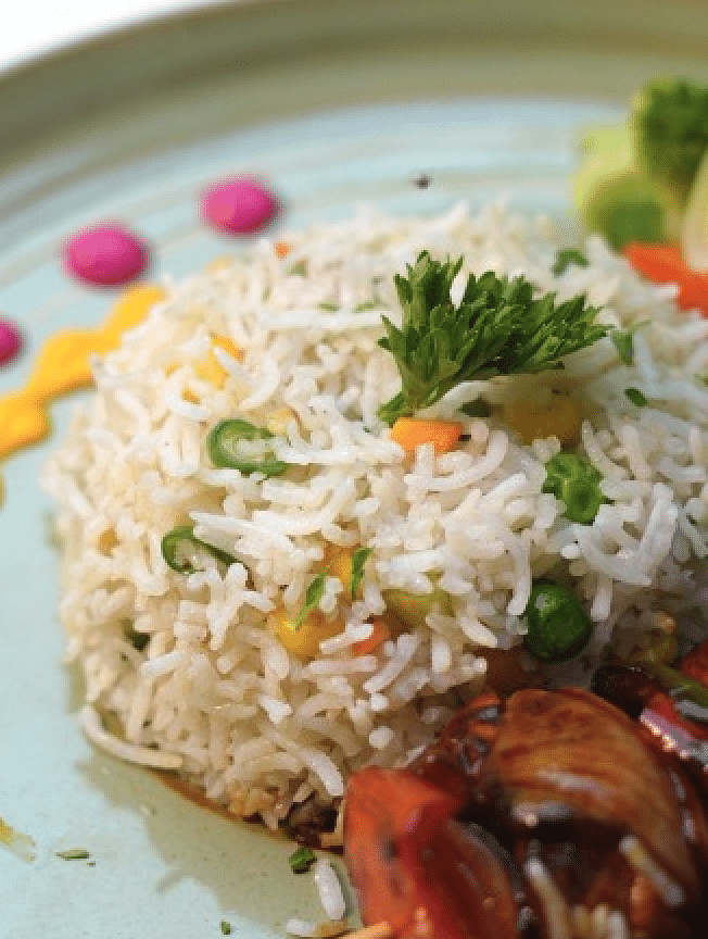 A beautifully plated dish with rice, meat skewers, and fresh herbs at Cenneys Gateway.