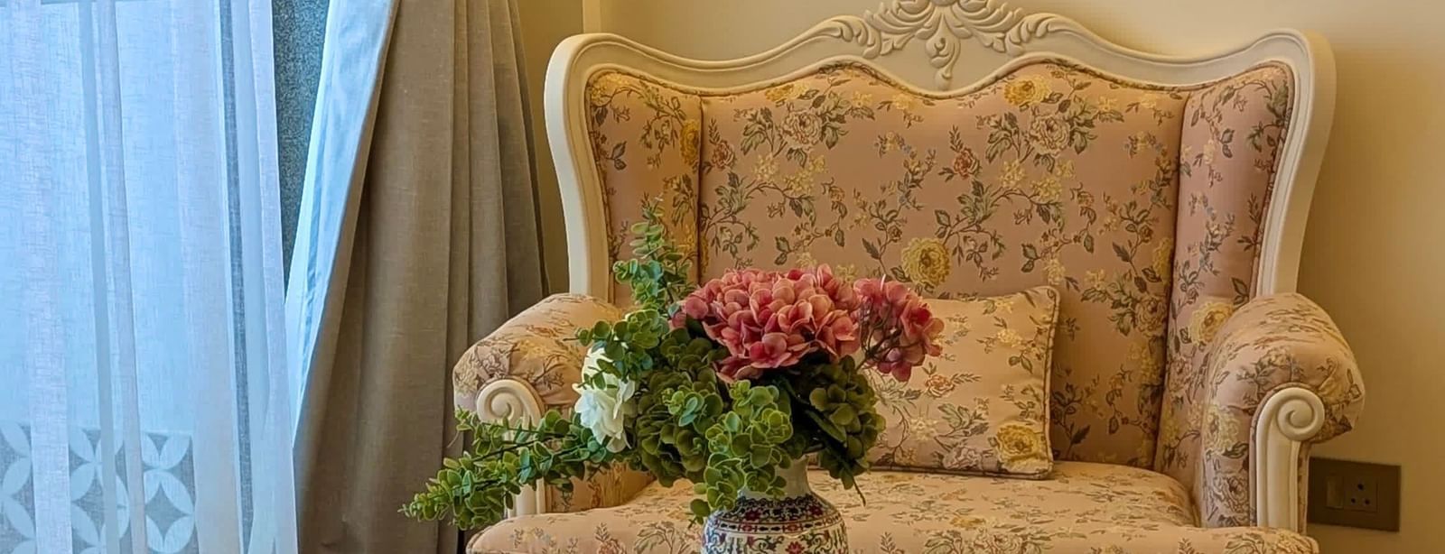Elegant armchair and side table by a sheer curtain, creating a cosy reading corner - Mayfair Cafe & Suites, Dalhousie