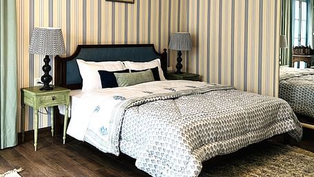 Image of Family Suite with bed, photoframs above the bed and large rug by the feet of the bed | Faraway Cottages, Auli