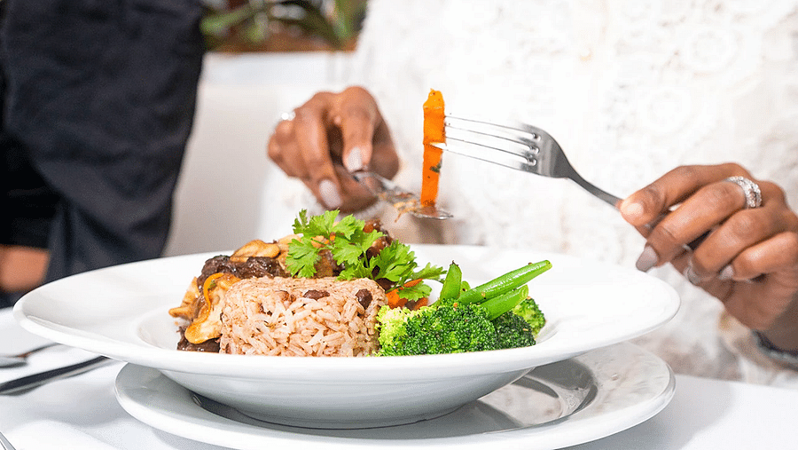 A woman dressed in white enjoying a sandwich in our restaurant in Kingston - S Hotel Kingston, Jamaica