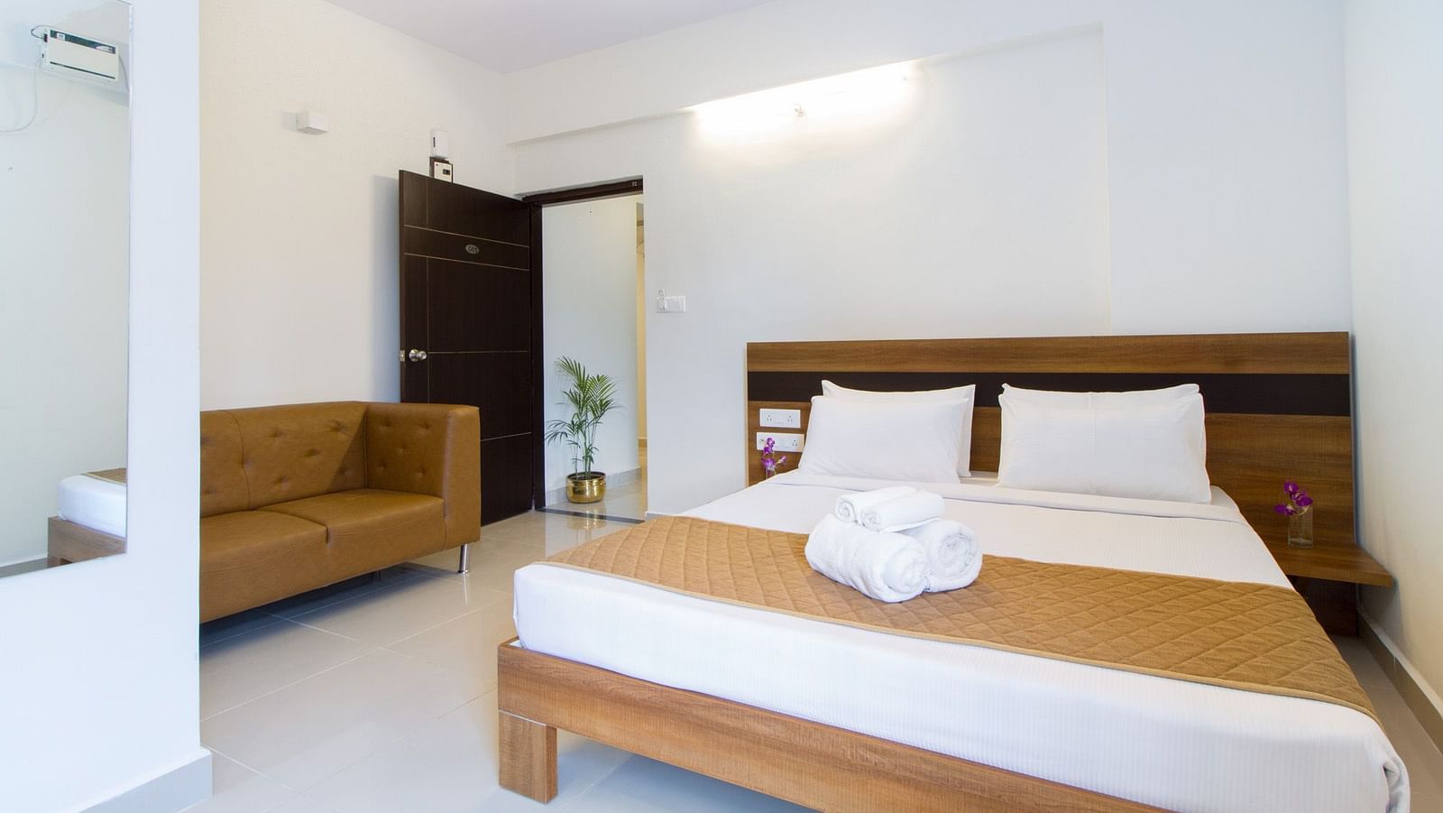 A hotel room including a double bed with bedding and an armchair at Sanctum Suites Whitefield, Bangalore.