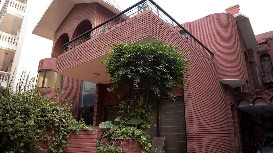 Redbrick Home - image of the facade featuring walls made from red bricks and plants growing in the premises