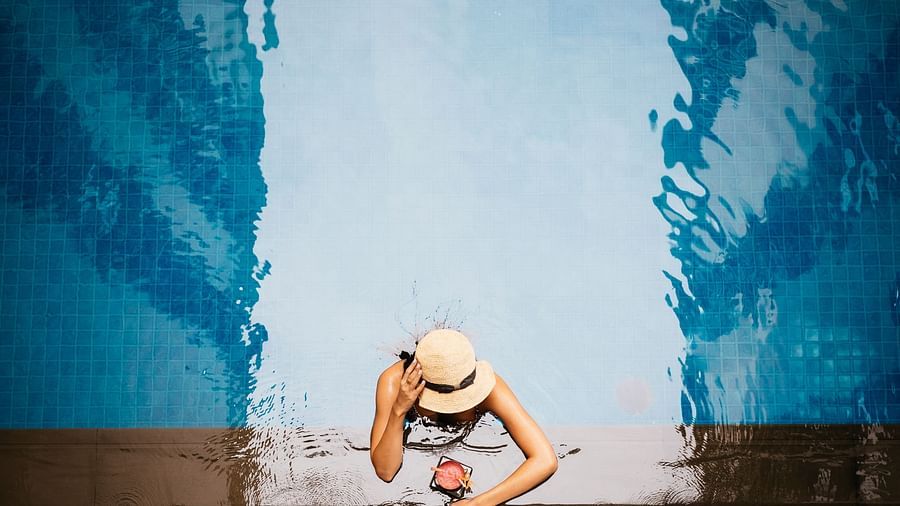 A woman wearing a hat is relaxing near the edge of the pool | Central Mansions, Phnom Penh