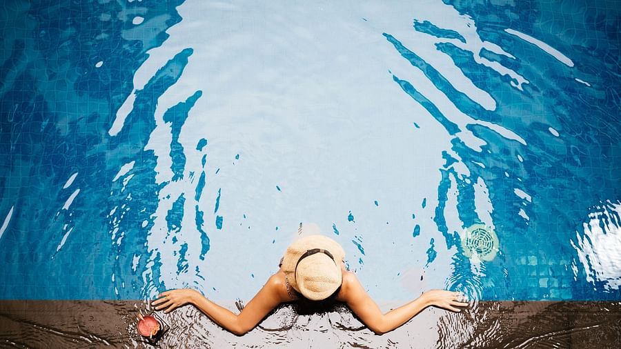 A woman is floating near the edge of the pool with a hat on her head | Central Mansions, Phnom Penh