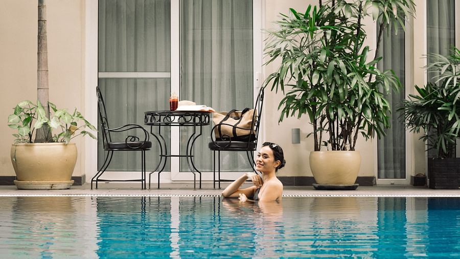 A woman resting in a swimming pool with chairs in the background | Central Mansions, Phnom Penh