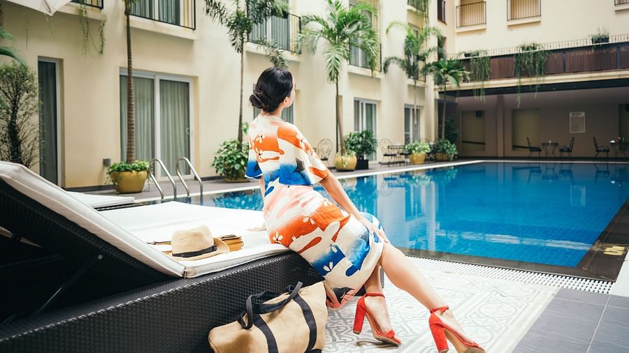 A woman is sitting on a lounge chair near a swimming pool | Central Mansions, Phnom Penh