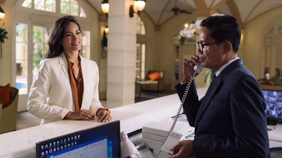 A hotelier on a call while the woman is standing near the reception desk | Central Mansions, Phnom Penh