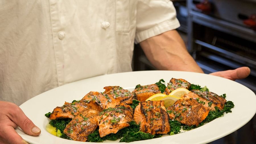 A chef carrying a Salmon dish on a white plate - Brewery Gulch Inn & Spa