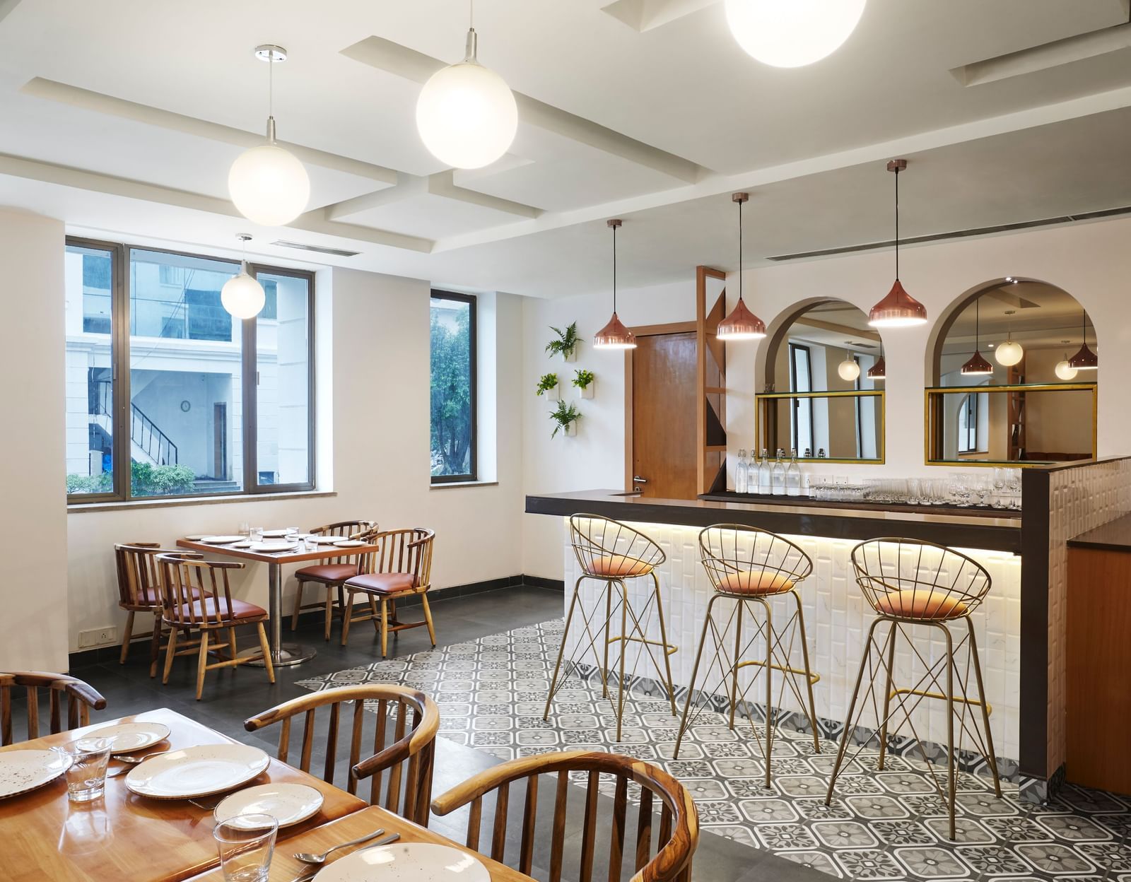 A wide view of the dining area at Monday Hotels Mahape, Navi Mumbai, with a bar and tables set for guests.