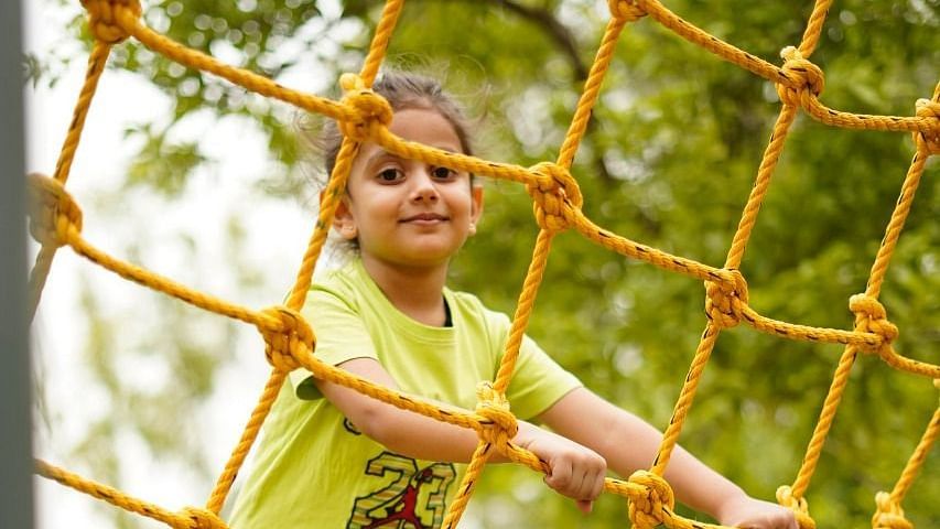 Kid on a commando net ride at inflated trampoline surrounded by trees at Themis Mudhouse - A Nature's Retreat Resort & Wellness