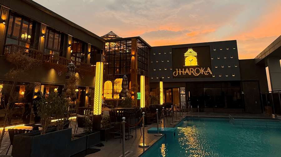 A swimming pool of Jharoka situated next to a building structure under a sky during twilight.