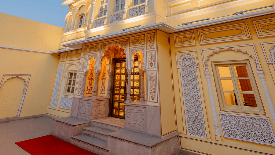 corner view image of the facade featuring a red carpet spread in front of the entrace - Brij Castle, Jaipur