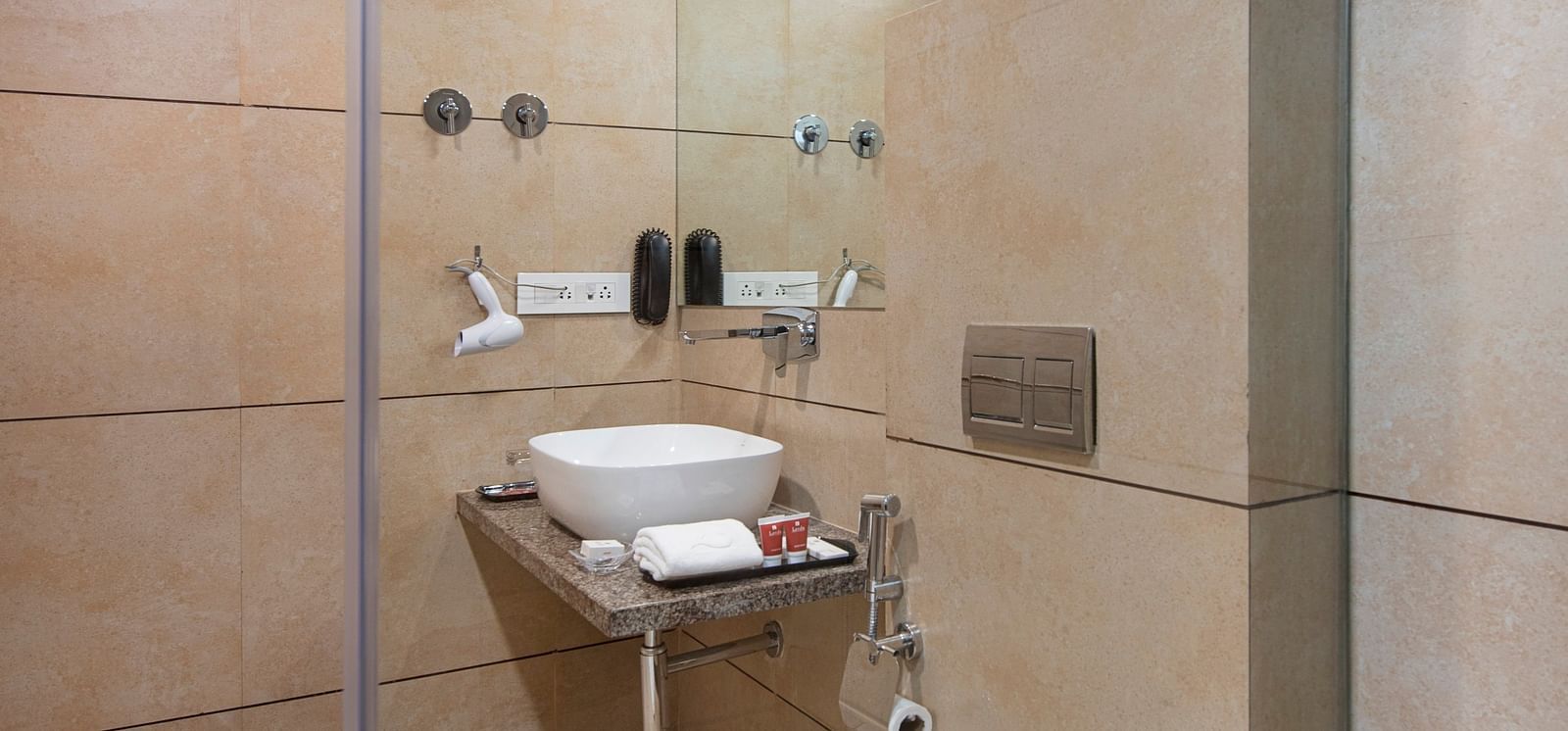 A compact hotel bathroom with a toilet and sink - SK Lords Inn Ahmedabad