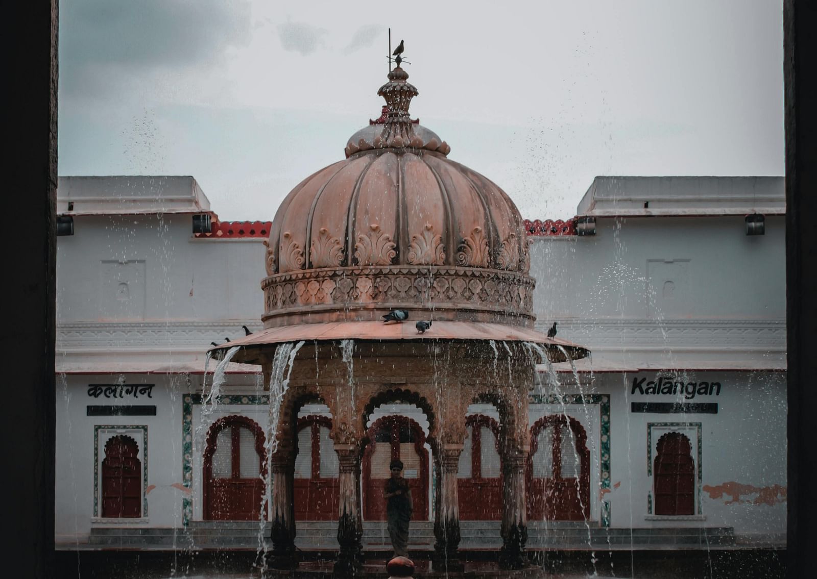 A brown concrete fountain in front of a white building, of Saheliyon ki Bari.