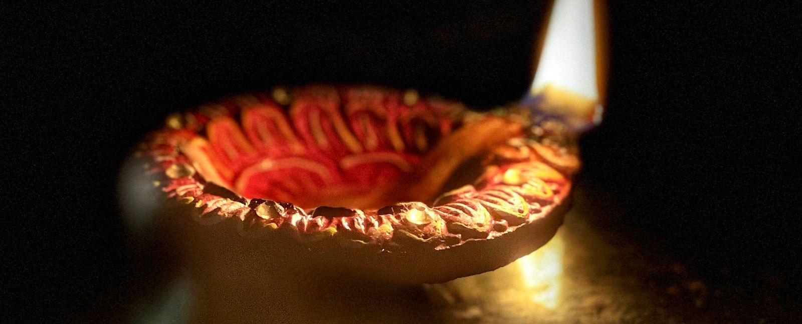 A close up of a lit diya used for many celebrations, including Karthigai Deepam.