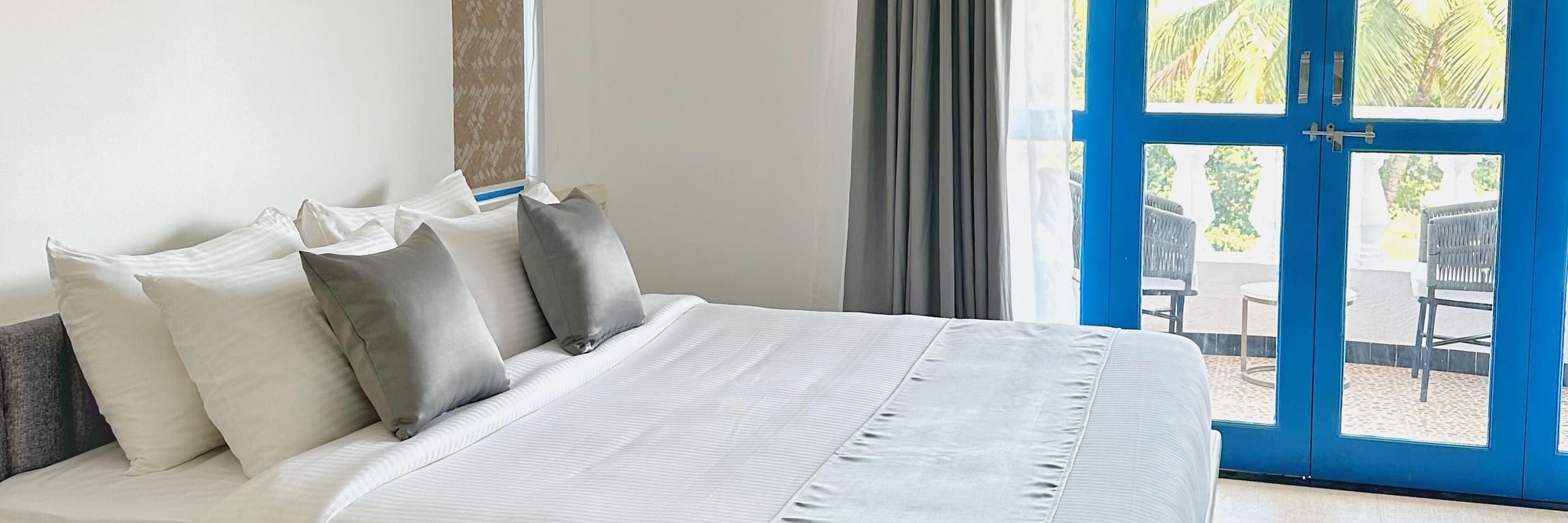 A king bed with blue door to the balcony inside one of the rooms at Azalea By Stone Wood Premier, Orlim