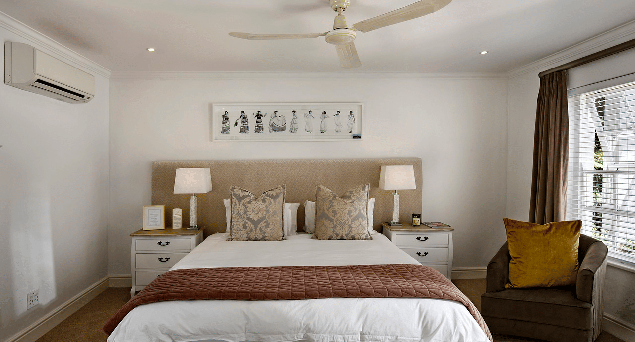 A double bed with a ceiling fan hanging over it in a bedroom.