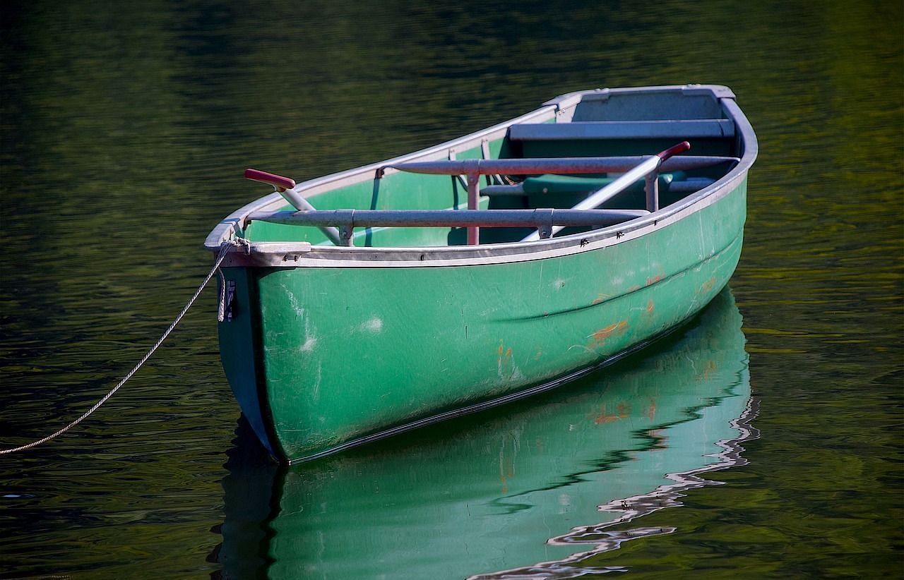 Close-up of an empty boat gently floating on calm water, reflecting the serene surroundings.