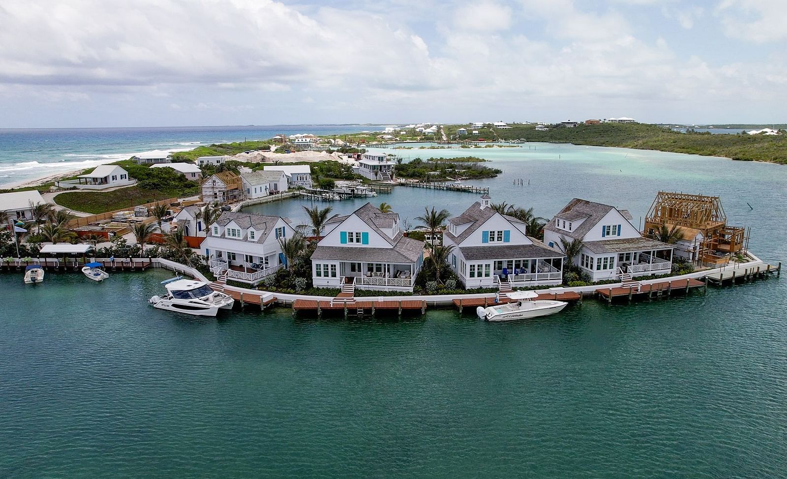 Marina scene with small boats docked near a group of seaside cottages and overwater villas in a protected inlet | Abaco Inn