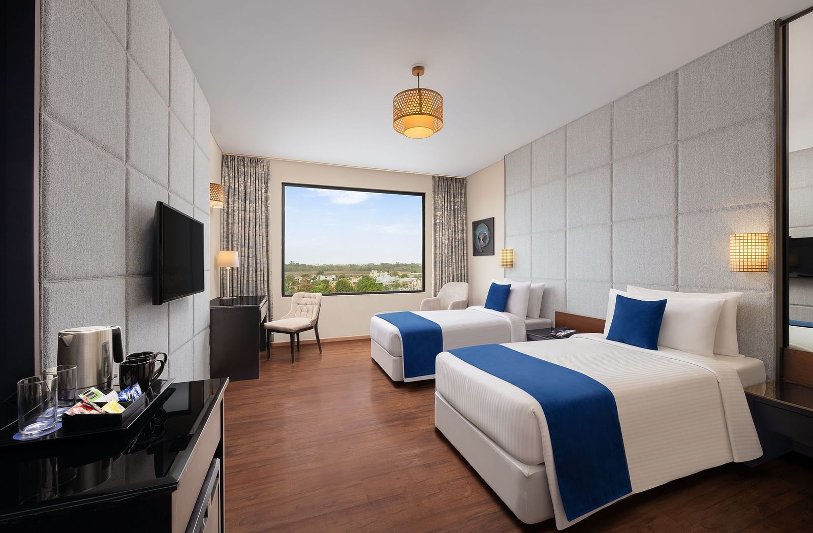 Deluxe Twin Room at Essentia Luxury Hotel, Indore with twin beds, a television and a work desk and chair